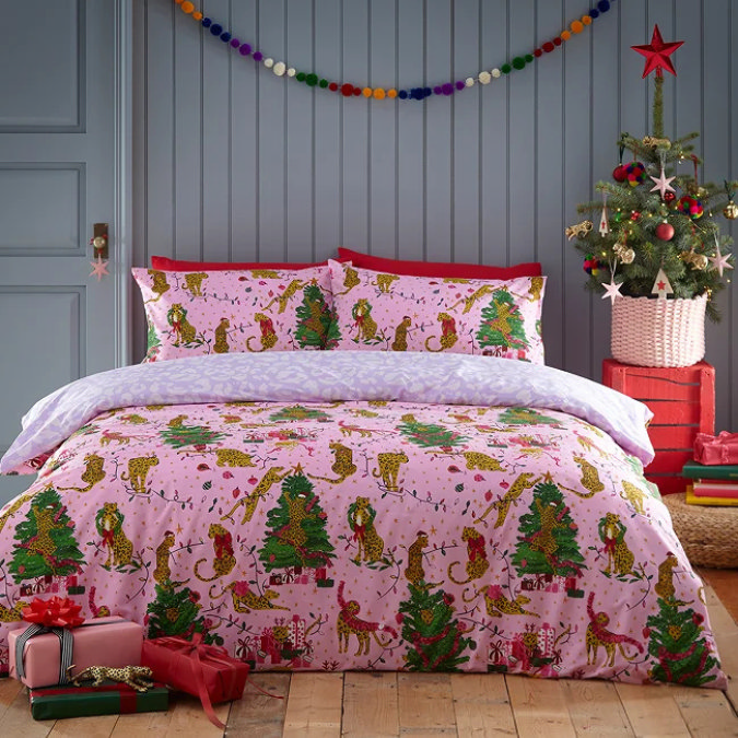 Pink Christmas bedding with festive leopard and Christmas tree print, styled with colourful garland and decorated tree