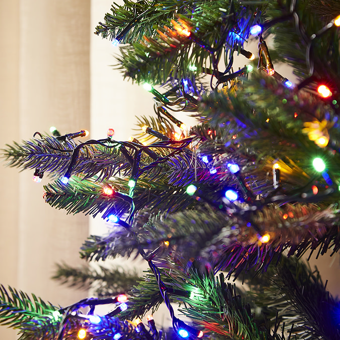 close up image of multi coloured lights on the branches of a green christmas tree