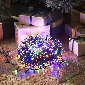 multi-coloured christmas lights wrapped up in a circle on a wooden floor, lit up in the dark