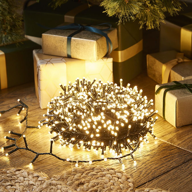 warm white christmas tree lights with 25m cable wrapped in a circle and lit up on a wood floor in the dark