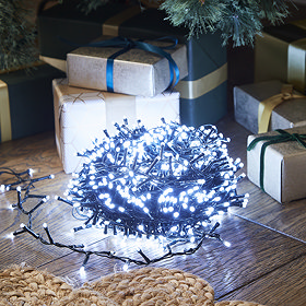 ice white LED lights on cable, wrapped up in a circle and lit up in the dark on a wooden floor underneath a tree