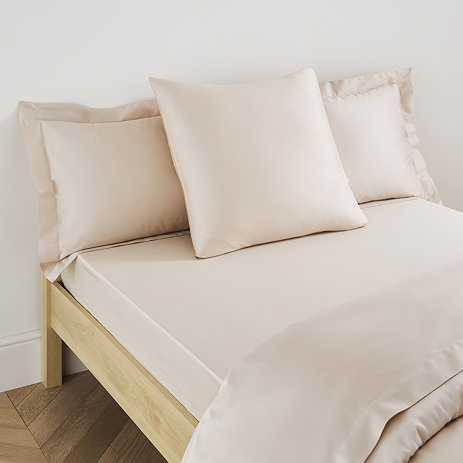 square pillow in natural cotton sateen pillowcase, between two standard pillows, at the head of a bed