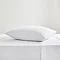 square pillow in white pillowcase on top of matching flat sheet on bed