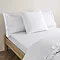 square pillow in white cotton sateen pillowcase, between two standard pillows, at the head of a bed