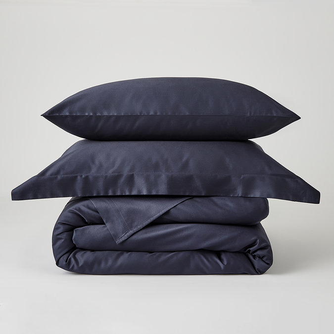 dark blue duvet cover folded with matching oxford and standard pillows stacked on top