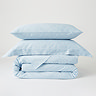 image of light blue duvet cover folded with matching oxford and standard pillows stacked on top, with plain white background
