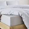 close-up on corner of bed with silver fitted sheet over the mattress, matching duvet set pulled back to reveal fit, and matching pillowcases
