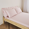 mattress on a bed covered with pale pink fitted sheet in standard size, with matching pillowcases