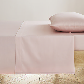 blush pink flat sheet neatly pressed on bed with matching pillow
