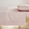 blush pink flat sheet neatly pressed on bed with matching pillow