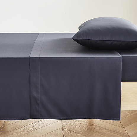 dark blue fitted sheet pressed neatly on bed with matching pillowcase