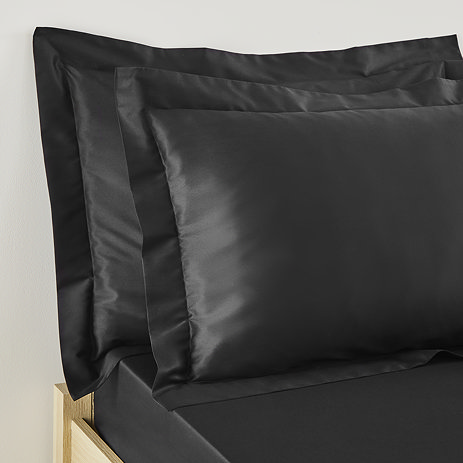 pair of pillows in black oxford pillowcases propped up at head of bed