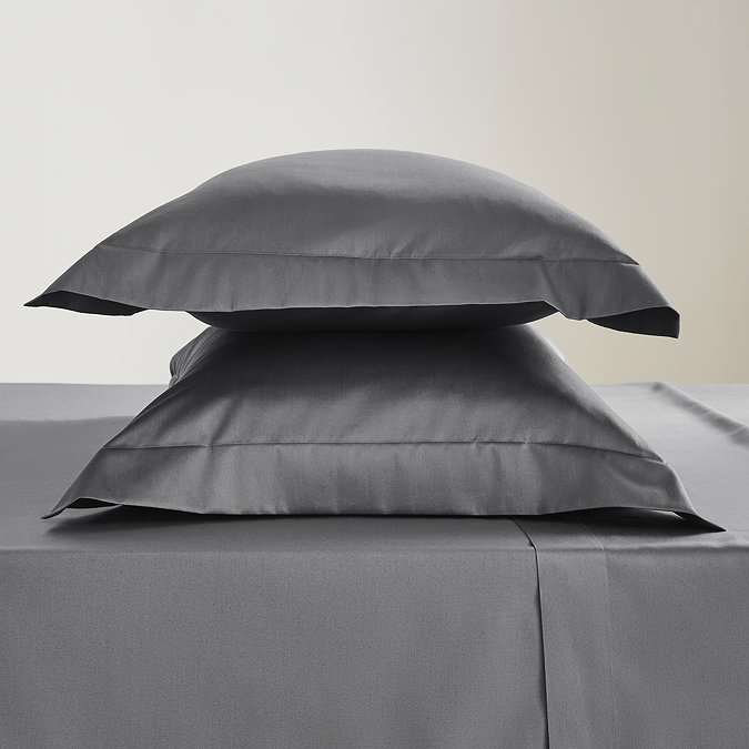 two pillows in charcoal grey pillowcases stacked one on top of the other on a matching flat sheet