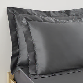 two pillows in charcoal grey pillowcases propped up at the head of a bed