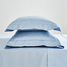 two pillows in light blue oxford pillowcases stacked one on top of each other on matching flat sheet
