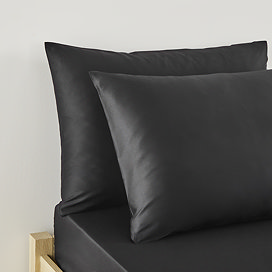 close up on two pillows in black pillowcases at top of bed