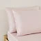 close up on pair of pillows in blush pink pillowcases, at top of bed with matching pink fitted sheet