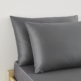 close up on pair of pillows in charcoal grey pillowcases at head of bed