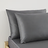 close up on pair of pillows in charcoal grey pillowcases at head of bed