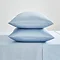 two pillows in light blue pillowcases stacked one on top of the other on top of matching blue flat sheet