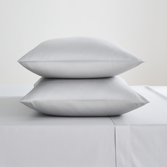 two pillows in silver pillowcases stacked one on top of the other on matching silver flat sheet