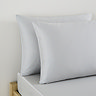close up on two pillows in silver pillowcases at head of bed with matching silver fitted sheet