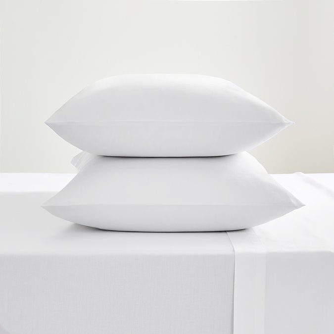 white cotton sateen pillowcase pair, stacked on on top of the other, on a flat sheet