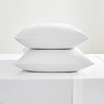 white cotton sateen pillowcase pair, stacked on on top of the other, on a flat sheet
