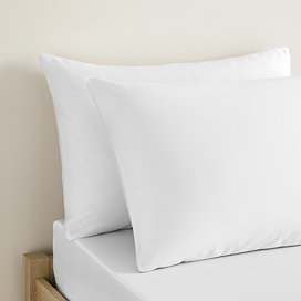 white cotton sateen pillowcase pair, one in front of the other, on a bed
