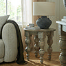 image of round rustic side table with carved legs, topped with ceramic lamp