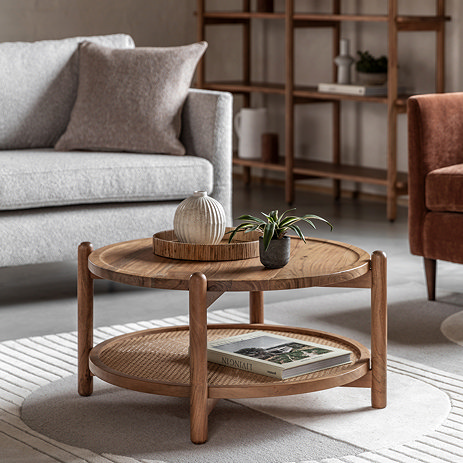 image of round acacia wood coffee table with rattan lower shelf, on rug of living room