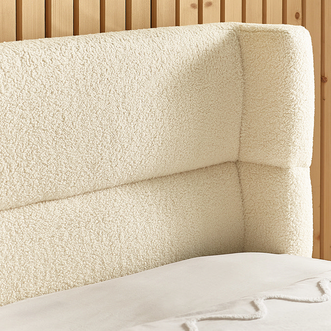 close up on boucle beige curved headboard of bed