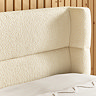 close up on boucle beige curved headboard of bed