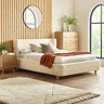 image of beige boucle textured bed with gently curved headboard, against slatted wood wall
