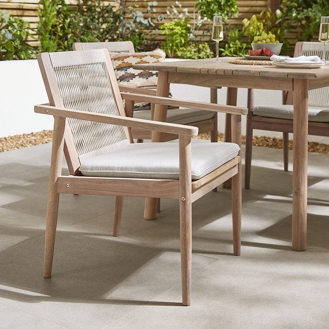 close up on acacia wood outdoor dining chair with rope back and cream cushion