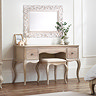ornate french inspired dressing table pushed up against white wall with intricate mirror above, complete with matching light wood fabric stool