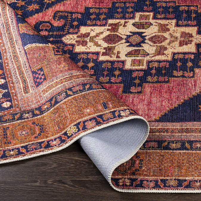 image of orange and red boho rug folded slightly to show its pile