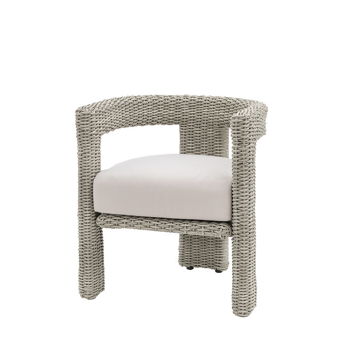 image cut out on white background of round backed wicker dining chair with plush cream cushion