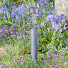 image of grey lantern-style stake light in flower bed of garden during the day