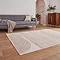 angled image of large rug in front of grey sofa on light wooden apartment floor