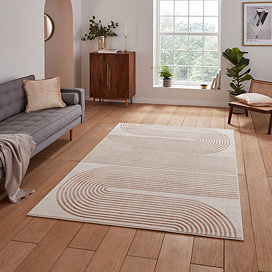 image of grey rectangular rug with large geometric wave pattern on it, on wooden floor in front of grey sofa in loft apartment