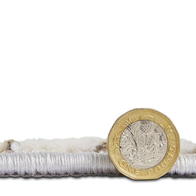 side-on image cut out on white background of grey rug with pound coin standing up next to it to show rug at half height of the coin