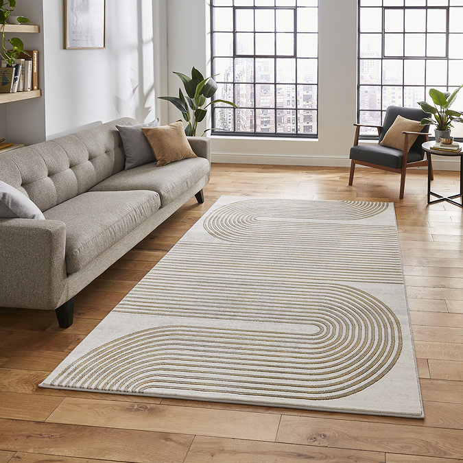 image of large rectangular rug with gold geometric swirl pattern in front of grey sofa