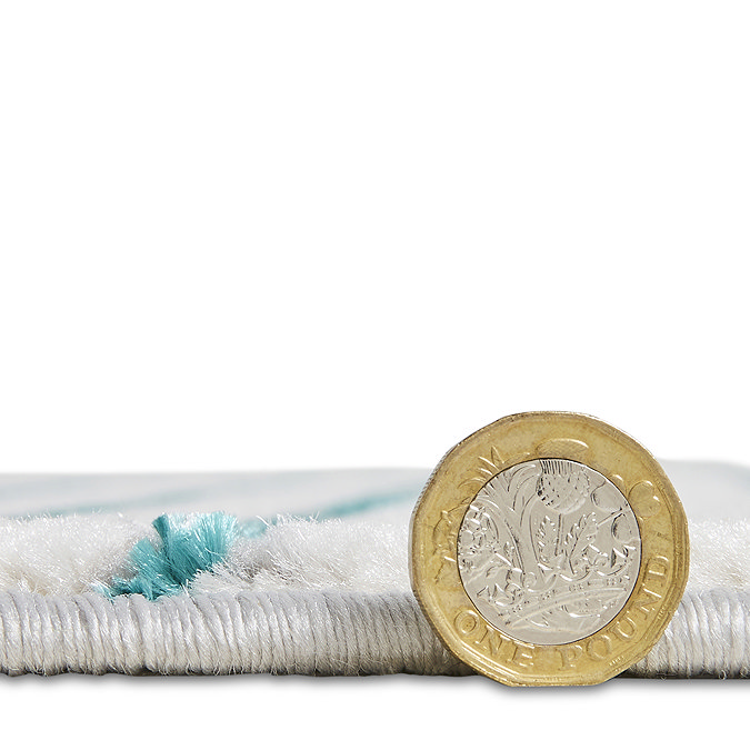 side on image of grey rug with pound coin next to it to show rug as half the coin's depth