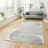 image of large rectangular grey rug with green geometric swirl pattern in middle of loft apartment