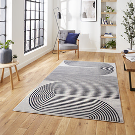image of large grey rectangular rug with navy swirl geometric pattern on wooden floor in modern loft apartment