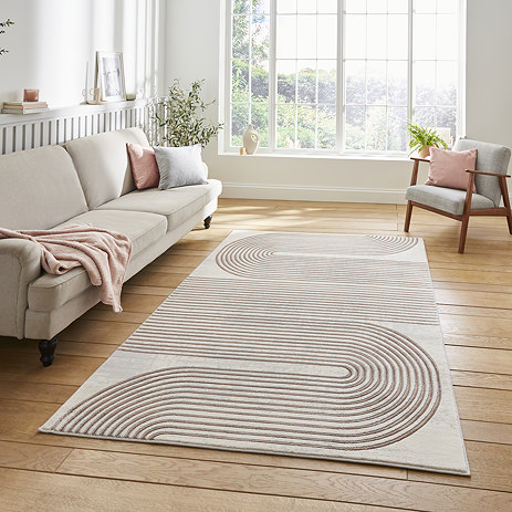 image of rectangular grey rug with geometric rose coloured weave, on wooden floor of modern loft apartment