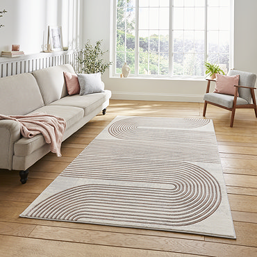 angled image of grey rectangular rug with rose coloured geometric weave, in front of cream coloured sofa with rose coloured throw