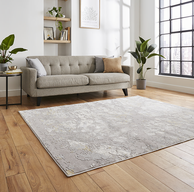 angled image of large grey/gold rug in front of a sofa