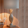 close up on lamp with wooden twisted base and linen shade, on an entryway table emitting a warm glow